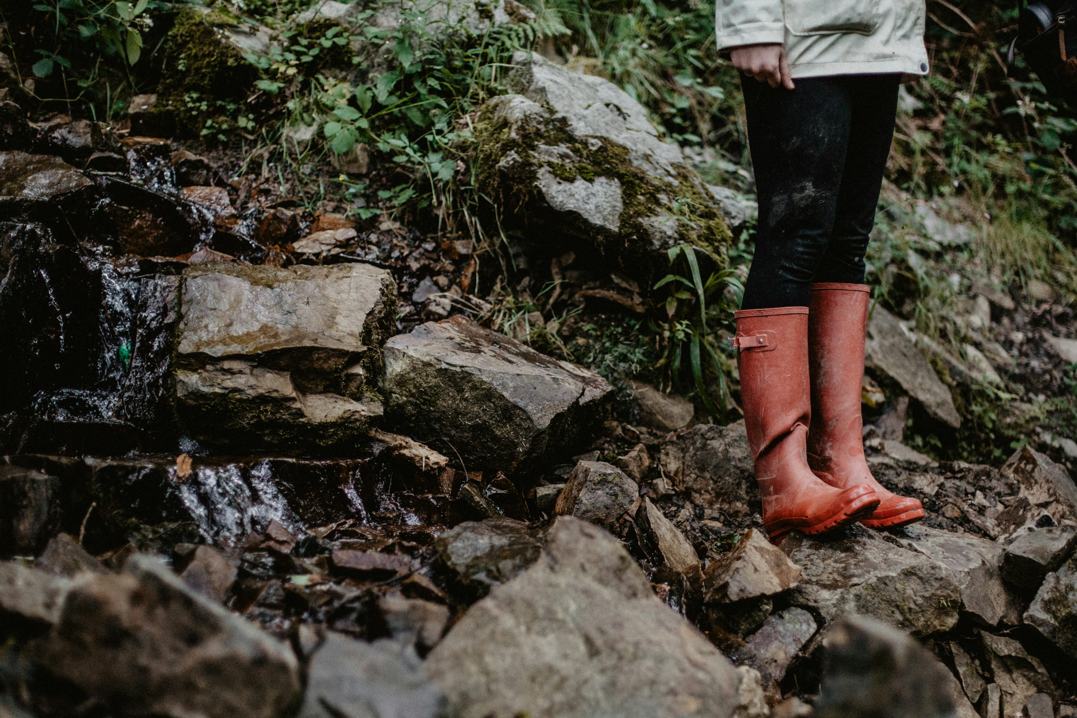 person in red leather boots standing on rocky ground